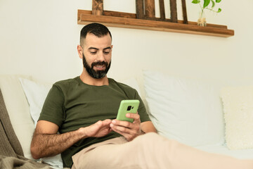 male amputee seating in sofa and looking at cell phone screen.