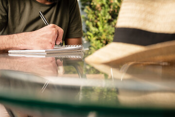 Obraz premium detail of man with partial hand amputation writing outside in journal or notebook.