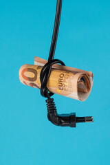 A fifty euro bill is inserted into a knotted knot of a power cable with a plug