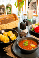Mexican tomato, bean, bell pepper soup and corn in the dark bowl.