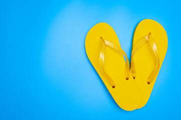 yellow rubber flip-flops isolated over blue background, pair of thongs, shot above