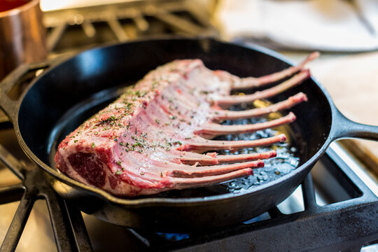 Rack of lamb cooking in cast iron skillet