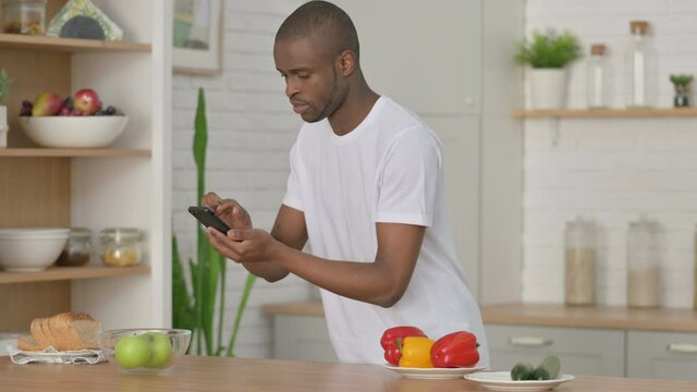 Sporty African Man Taking Picture of Fruits on Smartphone in Kitchen 