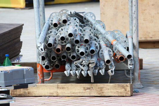 many pipes with adapters for assembling the scaffolding structure lie on the street next to the repair work.