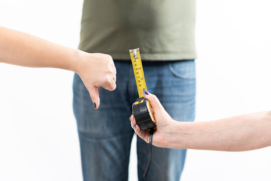 woman's hands disapproving of penis size, compared to a tape measure