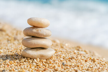 Pyramid stones balance on the sand of the beach. Zen balance, minimalism, harmony and peace. Selective focus