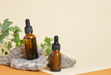 brown bottles for cosmetics with a pipette on a beige background, stones and a plant on the background, zero waste lifestyle