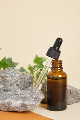 bottle for cosmetics with a pipette on a beige background, stones and a plant on the background, zero waste lifestyle