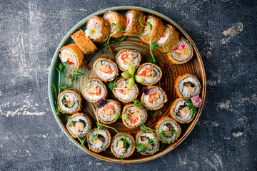 Assortment of delicious tempura and baked sushi maki with salmon, eel, cucumber, avocado, scrambled...
