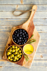 Top view of green and black olives in bowls with oil