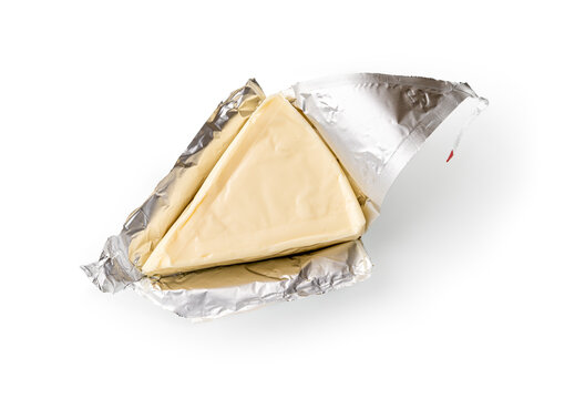 Foil wrapped processed creame cheese slice isolated on a white background. Small triangular piece of portioned soft cheese in a silver aluminium foil. Tasty sandwich ingredient. Macro.