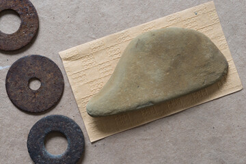 abstract composition with various isolated stones and rusty metallic washers on paper -...