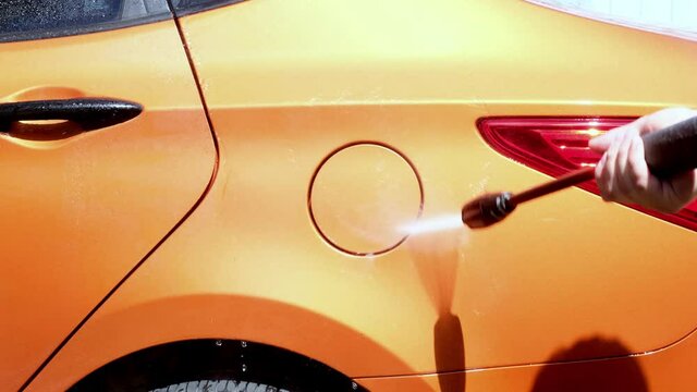 Manual car wash with pressurized water in car wash outside in summer.