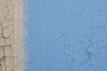 Blue peeling paint on the wall. Old concrete wall with cracked flaking paint. Weathered rough...