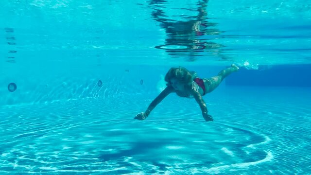 Cute young lady swimming underwater 