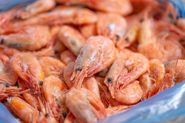 Pre-cooked and frozen shrimp close-up in a blue plastic bag. Dry freezing seafood. Selected focus