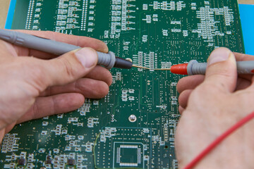 multimeter probes in the hands of an electronics repairman