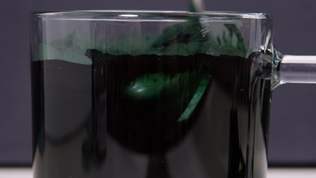 Green algae in powder spirulina dissolves in water. selective focus