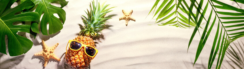 Pineapple with sunglasses on sand beach