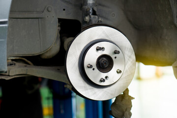 Disc brake of the vehicle for repair, in process of new 
 one disc replacement. Car brake repairing in garage.Close up.
