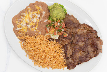 Overhead view of carne Asada steak cooked to perfection and served with rice and beans on a plate