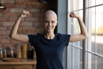 Happy strong female cancer patient flexing hands, biceps and fists, showing strength and confidence...