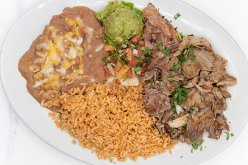Overhead view of shredded carnitas pork cooked to perfection and served with rice and beans on a plate