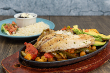 Seafood fajitas plate with large grilled fillet on top of veggies and shellfish