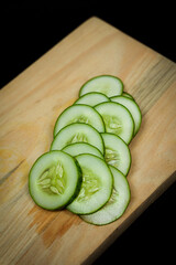 Fresh cucumber on a cutting board on a dark background. Cucumber is rich in nutrients such as vitamins C and K. Eating cucumber can also lower blood sugar in the body. Free copy space. Cucumber mockup