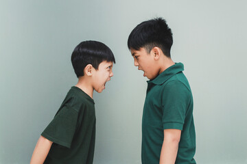 Two angry siblings looking each other and shouting each other on grey background