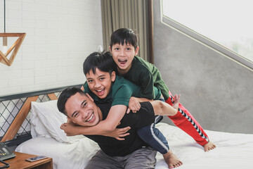 Happy sons hugging his father in bedroom
