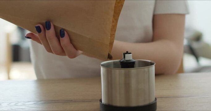 hands put coffee beans in grinder