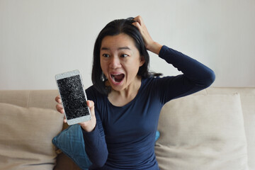 Confused angry woman having problem with phone sitting on couch at home