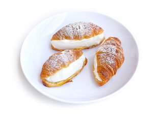 Fresh croissants with cream cheese on white plate.