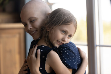Happy mom with cancer and daughter kid hugging, giving comfort and support to each other. Ill mother and child embracing, expressing love, tenderness, empathy, affection. Oncology, motherhood concept