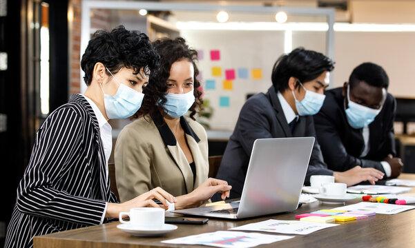 Multiracial smart formal businesspeople sitting face to face meeting and making group discussion at office, wearing face masks as new normal to protect or prevent virus in outbreak pandemic crisis.