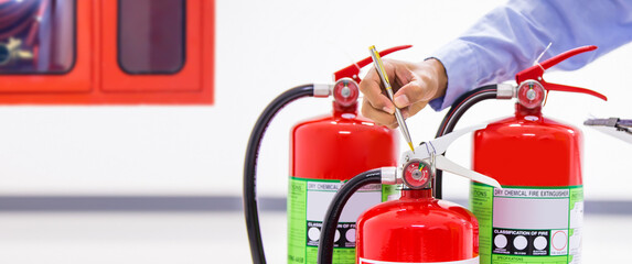 Fire extinguisher, Firefighter checking pressure gauge level of fire extinguisher tank in the building concepts of protection and prevent for emergency and safety rescue and fire training.