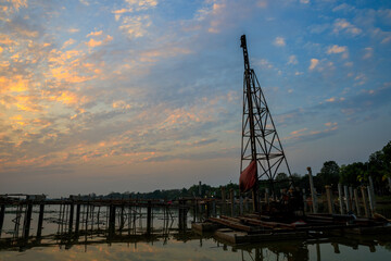 Obraz premium Stake crane at under construction site on the water lake at sunset or evening time with clouds scape.