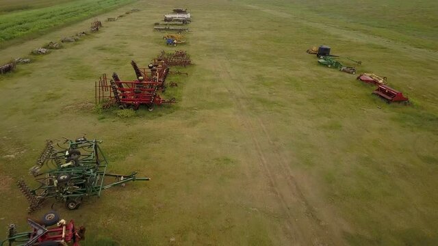 Aerial Tilt Up Shot Of Vehicles And Agricultural Machinery In Field, Drone Flying Over Green Landscape Against Sky - Oakley, Kansas