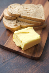 slice of butter and whole meal bread on chopping board 
