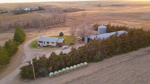 Aerial Panning Shot Of Houses In Agricultural Field, Drone Flying Over Harvested Land During Sunset - Oakley, Kansas