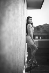 Vertical greyscale shot of a brunette female model posing in an elegant dress with one sleeve