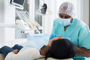 Dentist male in uniform is examinating of female in dental clinic