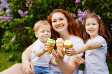 Selective focus. A happy family holds an open-air ice cream in front of them in a spring park against the background of blooming lilacs.