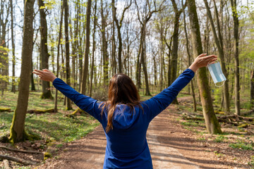 femme de dos se baladant en forêt au printemps libérée de son masque contre le covid 19