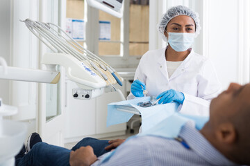 Dentist professional filling teeth for man patient sitting in medical chair