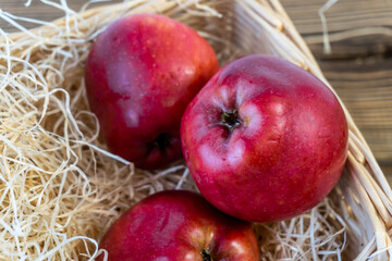 Red apples in a basket and on a wooden table