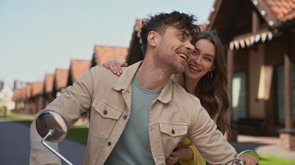 happy man and woman riding motorcycle outside.