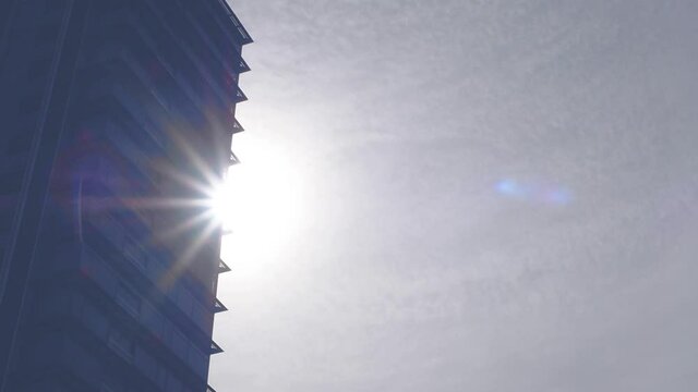 sunstar with silhouette building with transparent of clouds. bright sun shine through a black building. sky in summer season. hot weather forecast. big round sun spectrum. amazing natural phenomenon