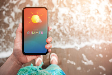 Summer Time Concept. Woman holding Mobile Phone with Summer Message and Icon Weather. Sand Beach with Sunlight as background. Top View © blacksalmon